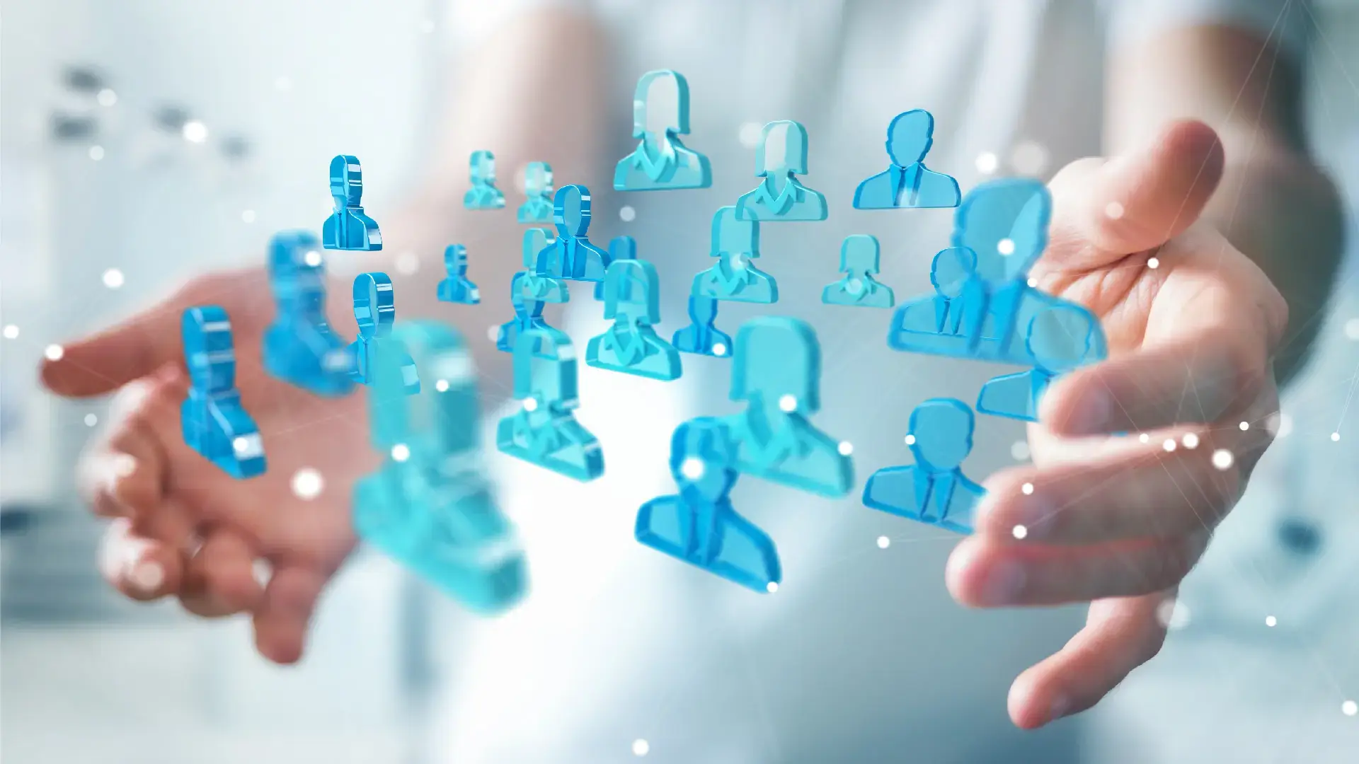 Close up image of a person's hands holding group of blue, 3D rendered figures